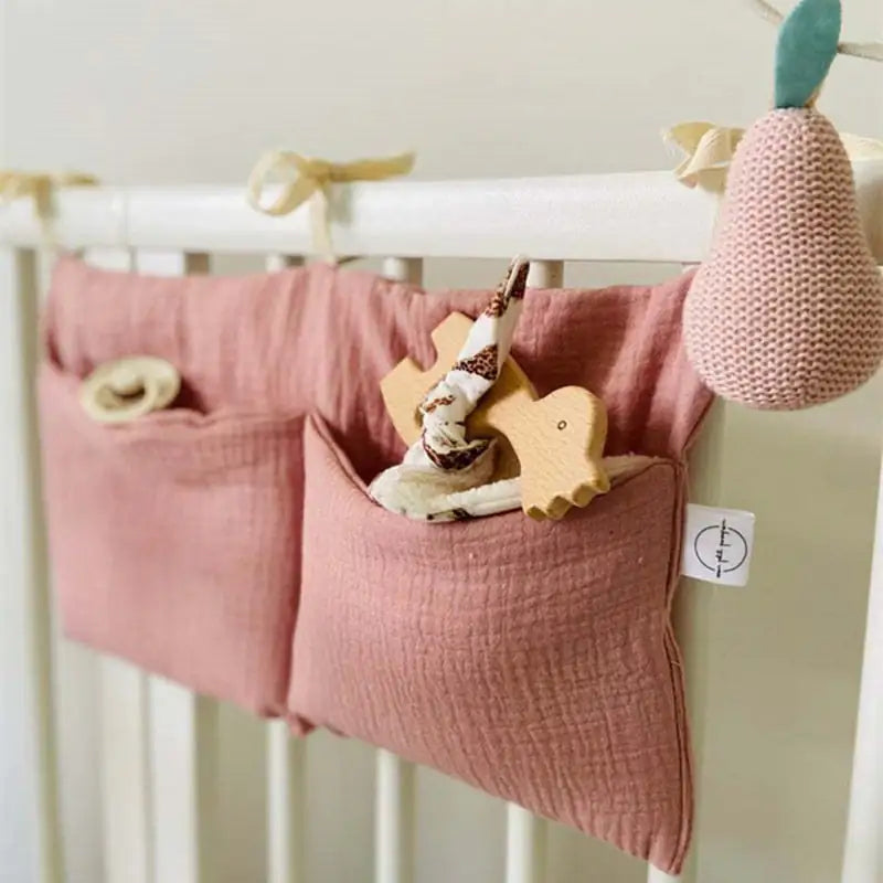 Photo of white crib railing with mauve pockets tied to them.