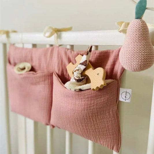 Photo of white crib railing with mauve pockets tied to them.