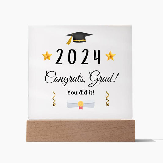 Square acrylic plaque with white background. Congrats, Grad message in the center. Set in a wooden base.