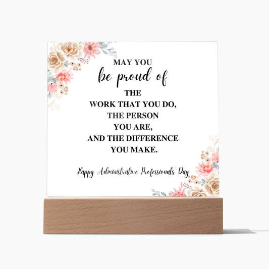Acrylic plaque on a wooden base. White background with flowers in top right and bottom left corners. Happy Administrative Professionals Day message in the center. 