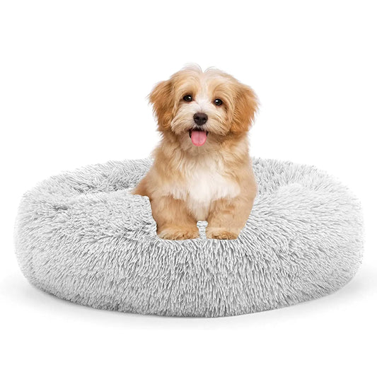 A puppy sits on a round, gray plush bed. 