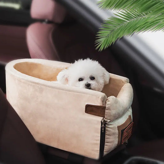 Picture of a small white dog in a beige walled bed, seated on the armrest of a car.